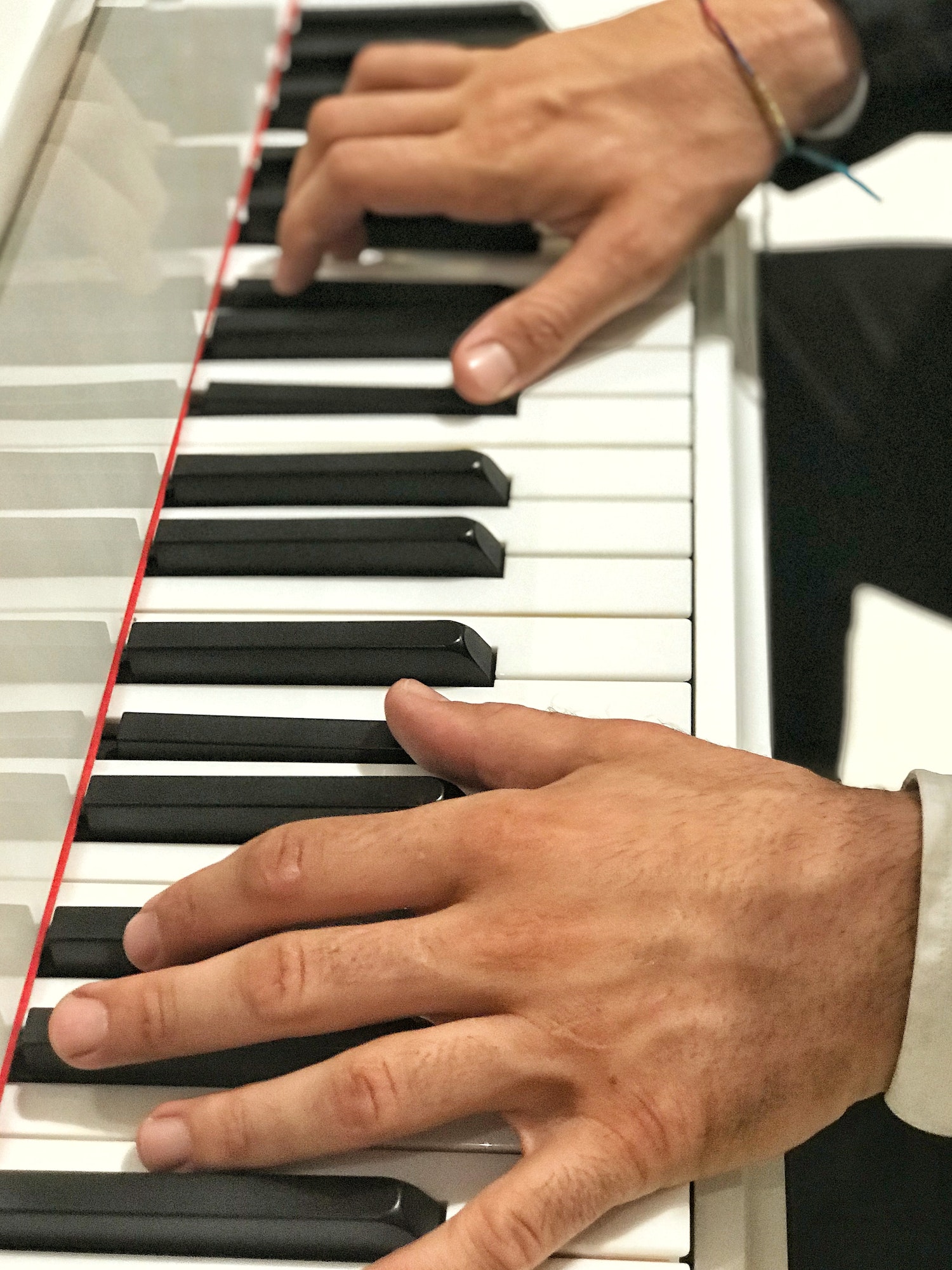 Unrecognizable person with large hands and long fingers playing Piano at a social event
