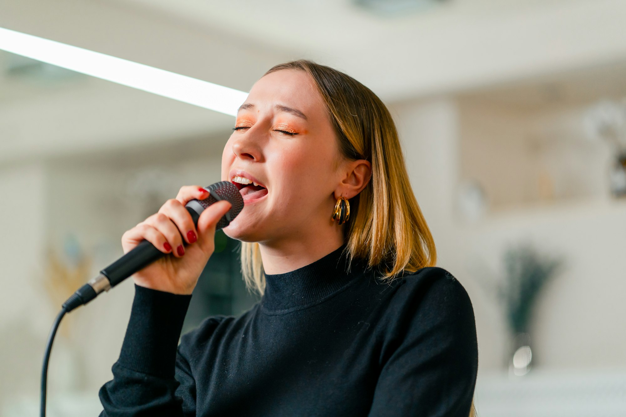 young girl sings in a vocal lesson with a microphone in her hands during a lesson at a music school