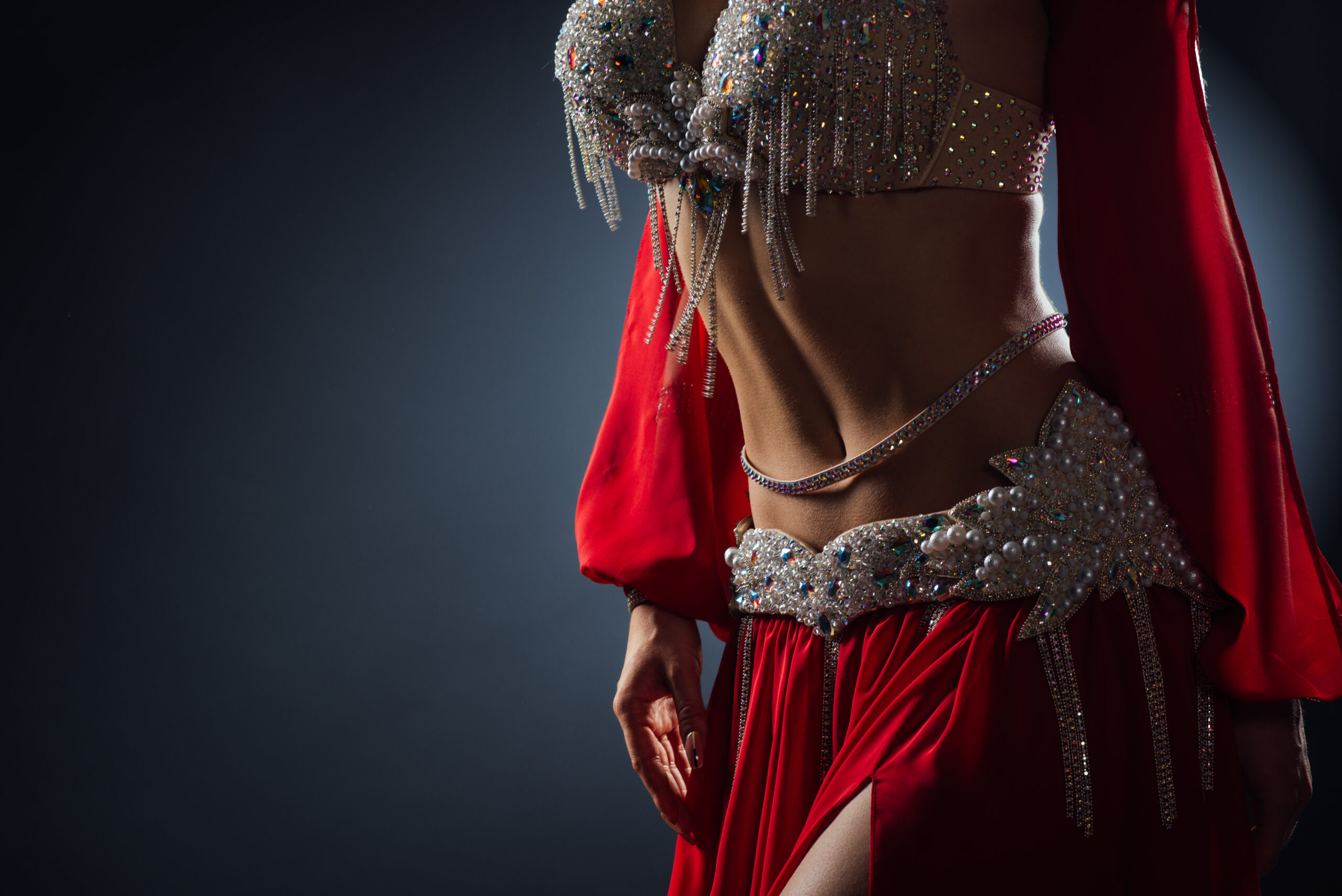 Beautiful belly dance of a girl in a red decorated ethnic dress in the dark