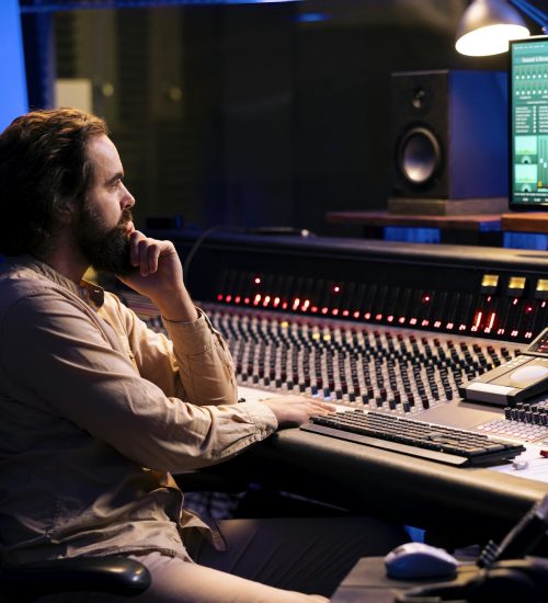 Tracking engineer uses audio console in professional recording studio