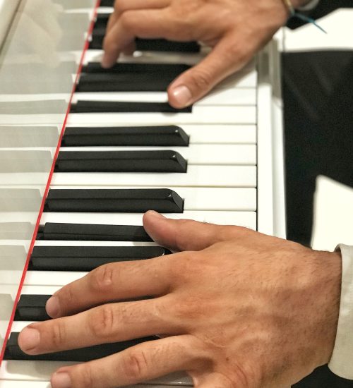 Unrecognizable person with large hands and long fingers playing Piano at a social event